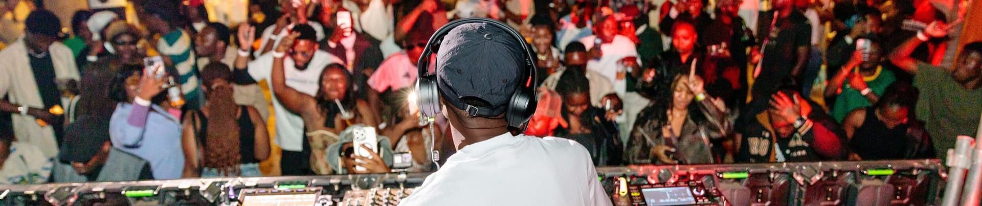 Ryan Synth at the decks in headphones, in front of a packed, dancing crowd