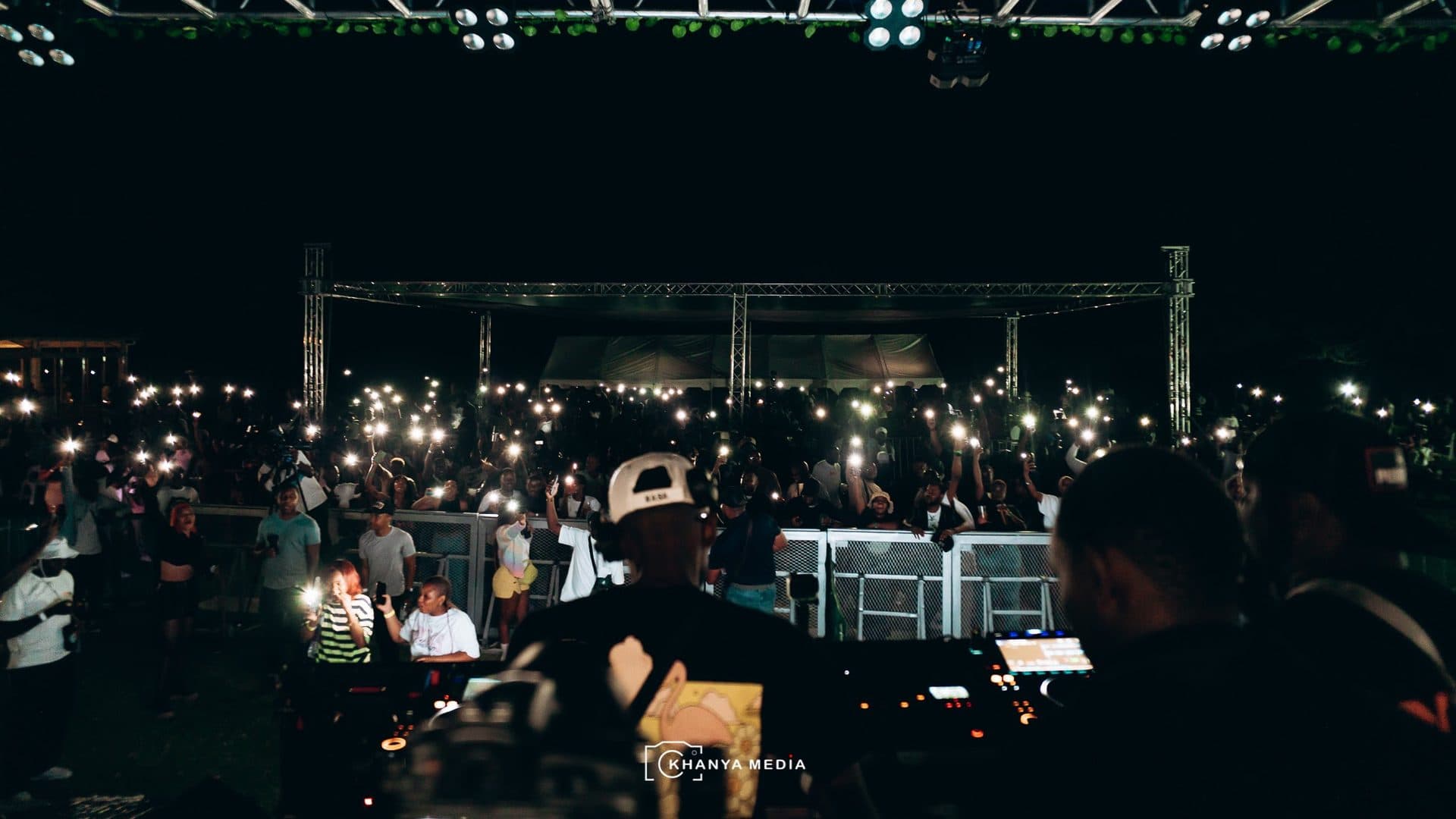 Ryan Synth's view from behind the decks at a night show, phone lights across the crowd